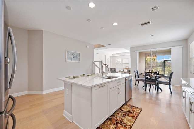 kitchen with a kitchen island with sink, sink, light hardwood / wood-style flooring, white cabinetry, and stainless steel appliances