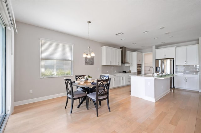 dining space with light hardwood / wood-style floors, sink, and a chandelier