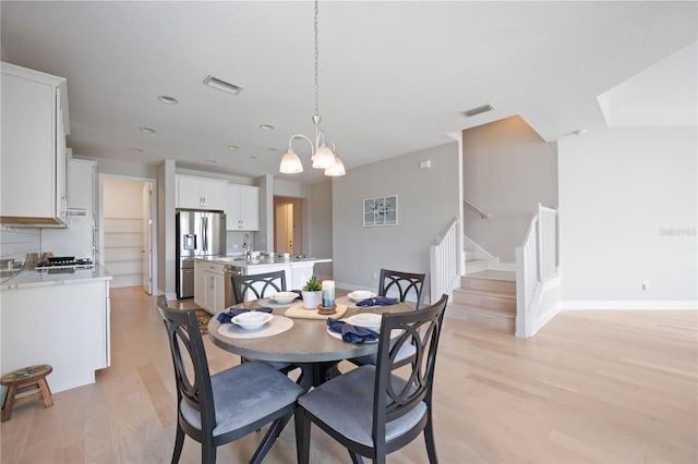 dining room featuring sink, a chandelier, and light wood-type flooring