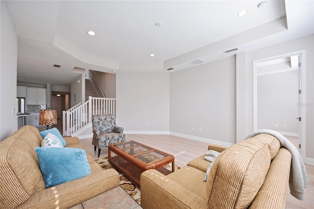 living room featuring light hardwood / wood-style floors and a raised ceiling