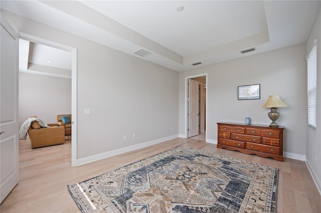 bedroom featuring light hardwood / wood-style floors and a raised ceiling