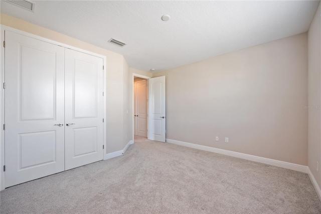 unfurnished bedroom featuring light carpet and a closet