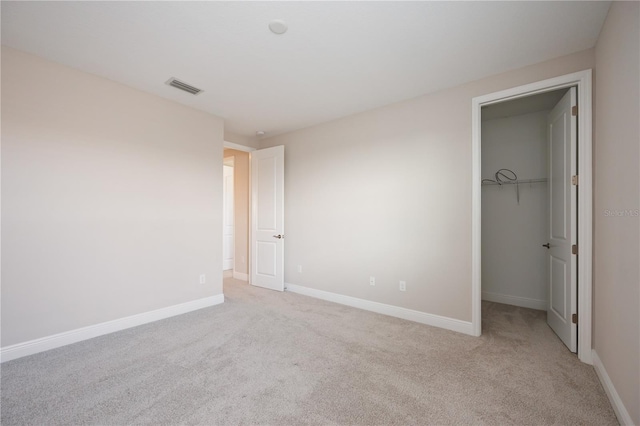 unfurnished bedroom featuring light carpet, a spacious closet, and a closet