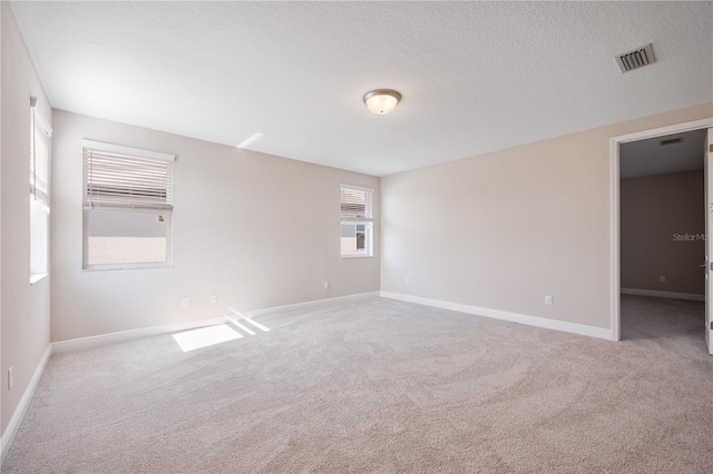 carpeted empty room with a textured ceiling