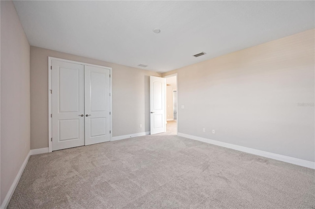 unfurnished bedroom featuring light carpet and a closet