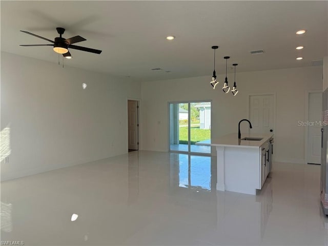 kitchen featuring sink, white cabinets, ceiling fan, an island with sink, and pendant lighting