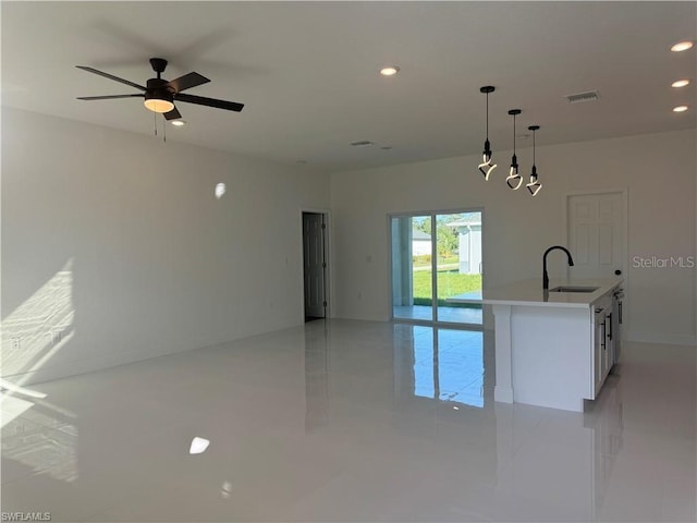 kitchen with sink, white cabinetry, ceiling fan, a center island with sink, and pendant lighting