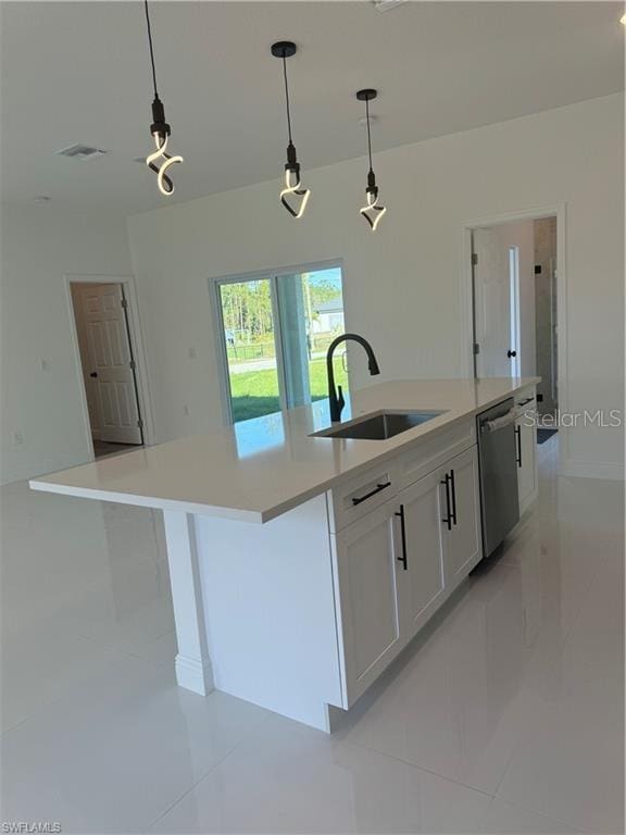 kitchen with stainless steel dishwasher, hanging light fixtures, an island with sink, white cabinetry, and sink