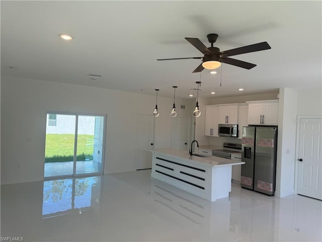 kitchen featuring sink, white cabinets, an island with sink, hanging light fixtures, and appliances with stainless steel finishes