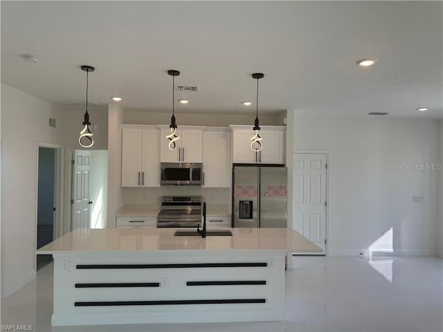 kitchen featuring white cabinets, a center island with sink, appliances with stainless steel finishes, and hanging light fixtures