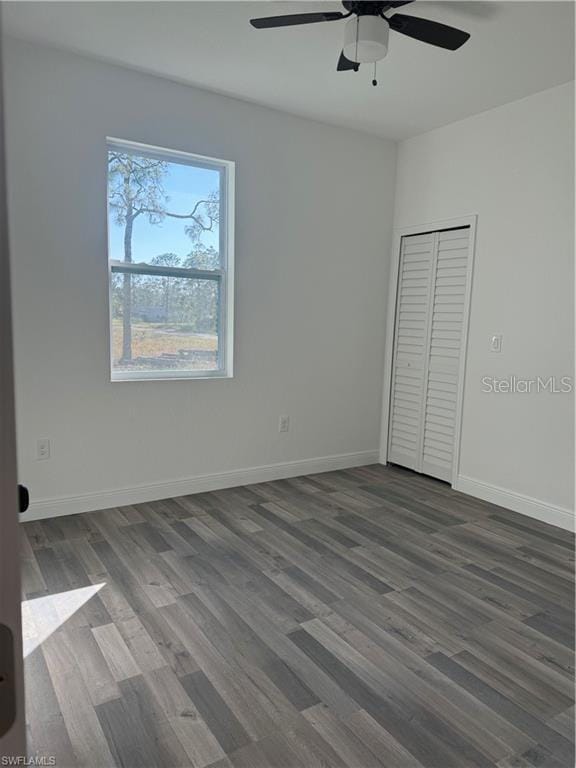 unfurnished bedroom with ceiling fan, dark hardwood / wood-style flooring, and a closet