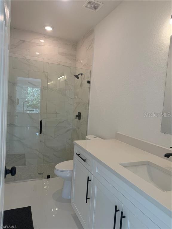 bathroom with toilet, a shower with shower door, and vanity