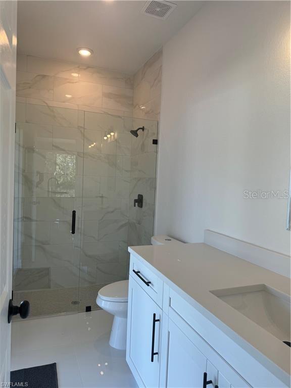 bathroom with vanity, tile patterned flooring, a shower with shower door, and toilet