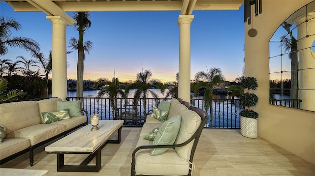 patio terrace at dusk featuring an outdoor living space and a water view