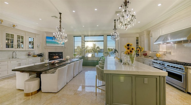 kitchen featuring a breakfast bar, a center island with sink, high end stainless steel range oven, green cabinetry, and decorative backsplash