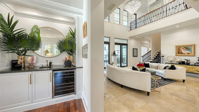 living room featuring plenty of natural light, a towering ceiling, beverage cooler, and wet bar