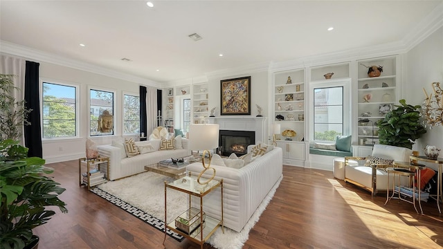 living room with hardwood / wood-style floors, built in shelves, and crown molding