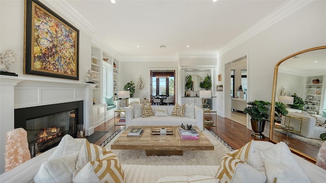 living room with built in shelves, ornamental molding, and wood-type flooring