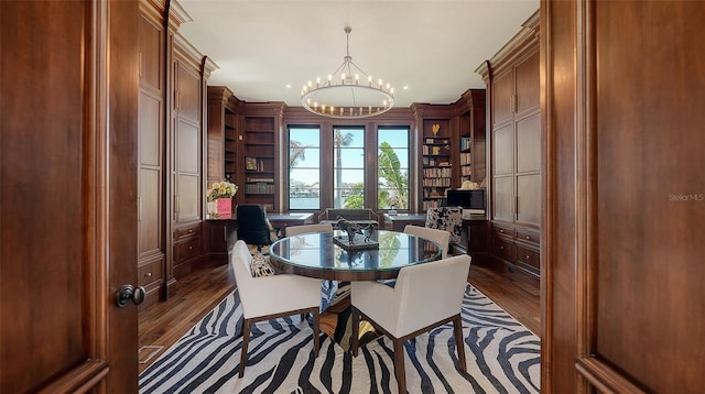 dining space featuring built in desk, dark wood-type flooring, and a notable chandelier