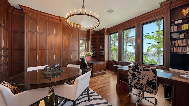 office space with built in shelves, light hardwood / wood-style floors, a notable chandelier, and wood walls