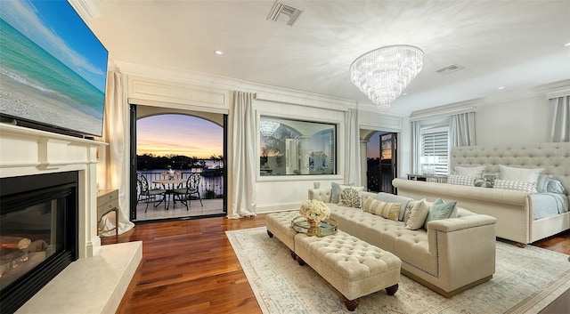 interior space featuring access to exterior, an inviting chandelier, a premium fireplace, wood-type flooring, and ornamental molding