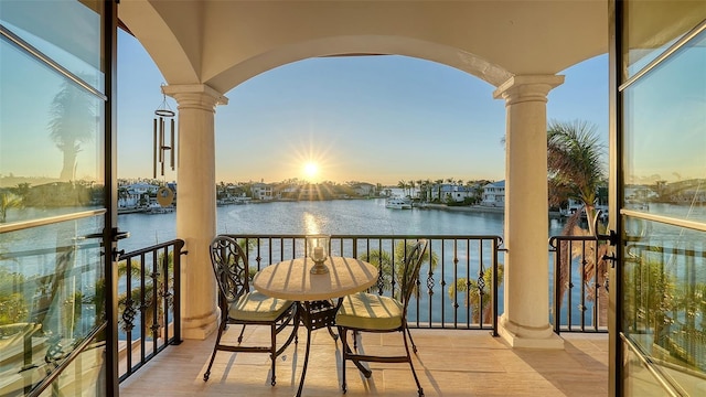 balcony at dusk featuring a water view