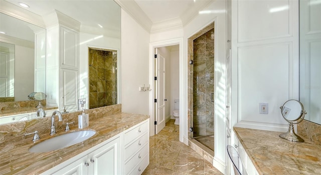 bathroom featuring vanity, toilet, ornamental molding, and tiled shower