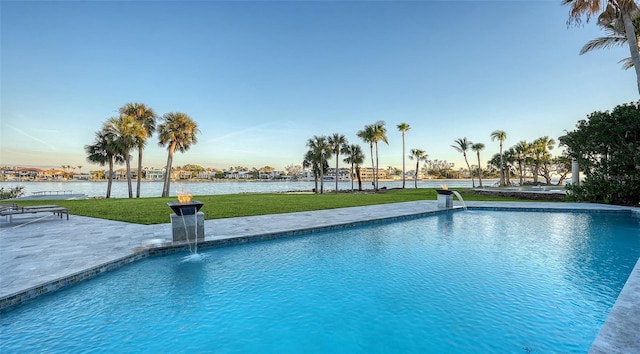 view of pool featuring a water view, pool water feature, a patio area, and a lawn