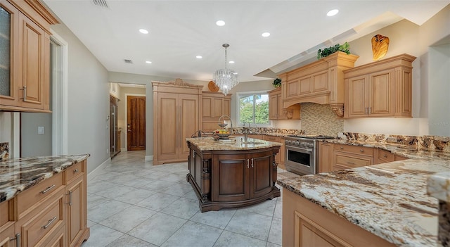 kitchen featuring stainless steel stove, light stone counters, decorative backsplash, sink, and decorative light fixtures