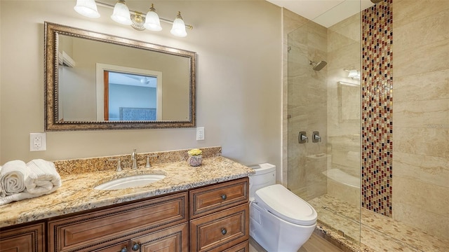 bathroom with toilet, tiled shower, and vanity