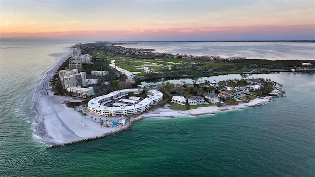 aerial view at dusk with a beach view and a water view