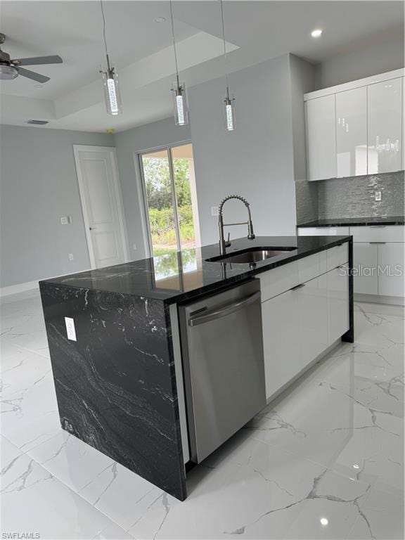 kitchen with dishwasher, an island with sink, a tray ceiling, white cabinetry, and decorative light fixtures