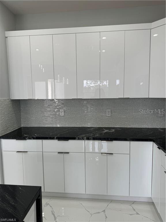 kitchen with white cabinets, dark stone counters, and decorative backsplash