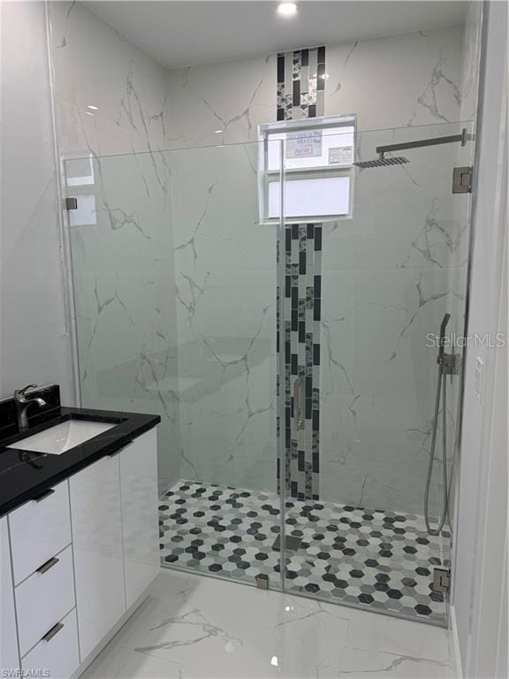 bathroom with a shower with shower door and sink