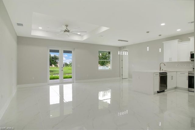 unfurnished living room featuring a raised ceiling, ceiling fan, sink, and french doors