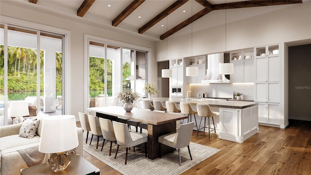 dining area featuring beam ceiling, hardwood / wood-style flooring, high vaulted ceiling, and sink