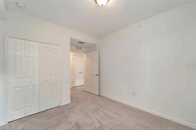 unfurnished bedroom with light carpet and a closet