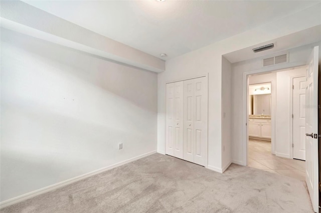 unfurnished bedroom with light colored carpet and a closet