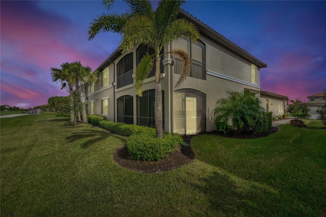 property exterior at dusk featuring a yard