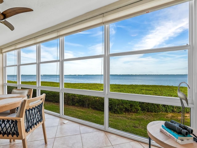 sunroom featuring ceiling fan and a water view