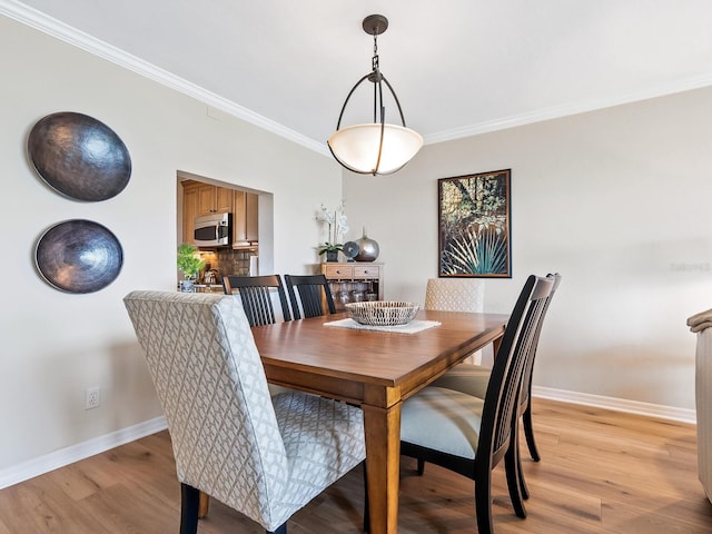 dining space with light hardwood / wood-style floors and ornamental molding