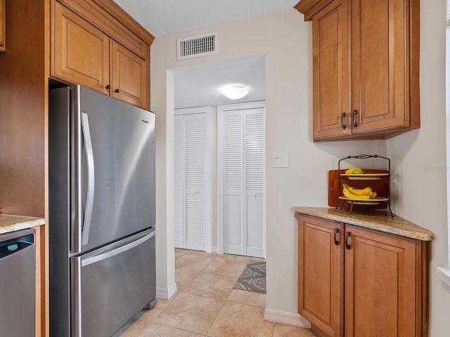 kitchen with light stone counters, light tile patterned floors, and appliances with stainless steel finishes