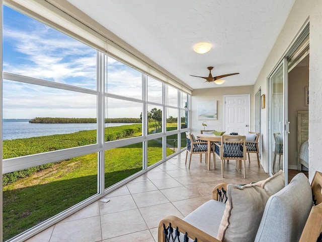 sunroom with ceiling fan and a water view