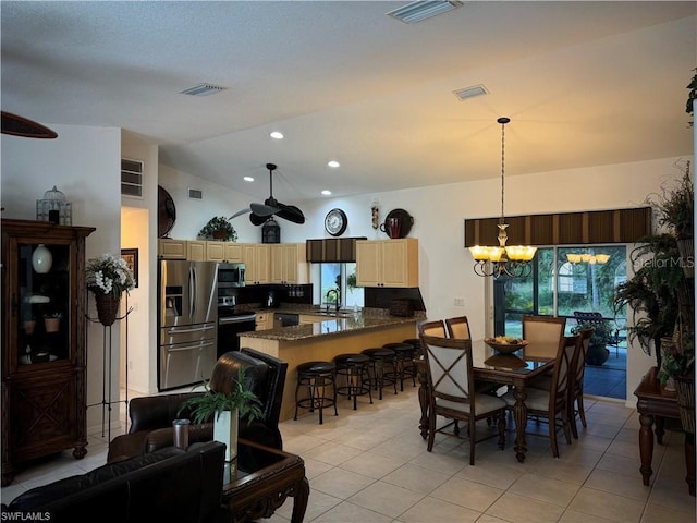 tiled dining area featuring sink, lofted ceiling, and ceiling fan with notable chandelier