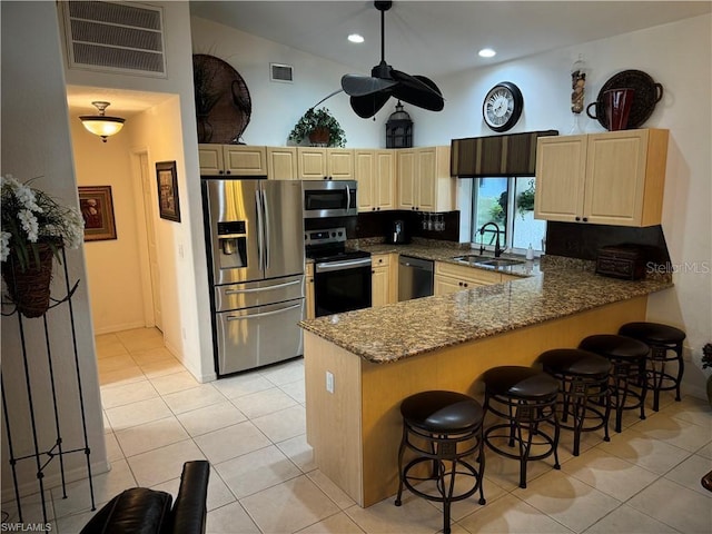 kitchen featuring kitchen peninsula, light stone countertops, stainless steel appliances, decorative backsplash, and sink