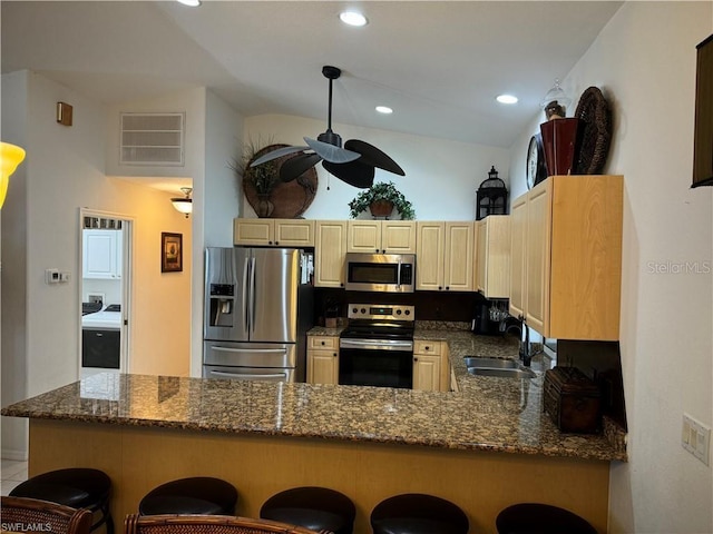 kitchen with appliances with stainless steel finishes, kitchen peninsula, a breakfast bar area, and sink