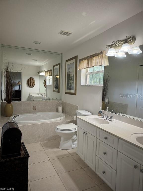 bathroom featuring toilet, tiled bath, tile patterned flooring, and vanity