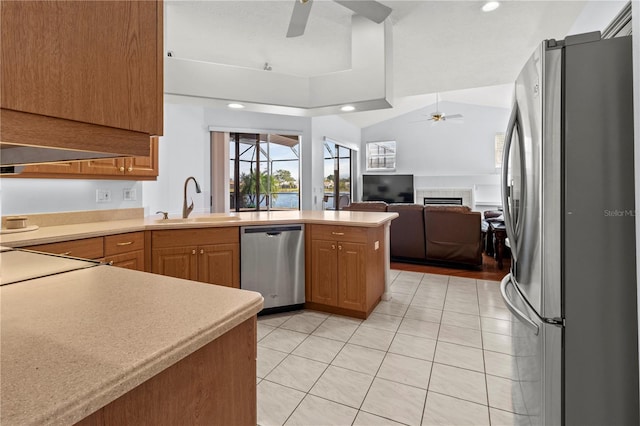 kitchen with sink, ceiling fan, light tile patterned flooring, kitchen peninsula, and stainless steel appliances