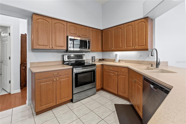 kitchen with sink, light tile patterned floors, and stainless steel appliances