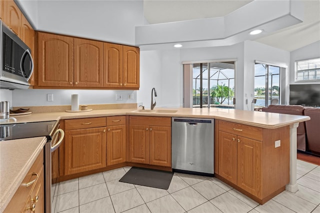 kitchen featuring kitchen peninsula, stainless steel appliances, vaulted ceiling, sink, and light tile patterned floors